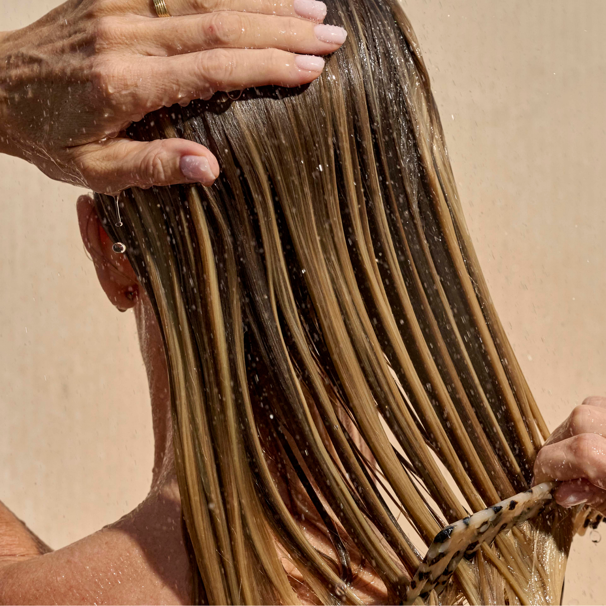 Woman applying Mela & Kera Balayage Conditioner to color treated hair